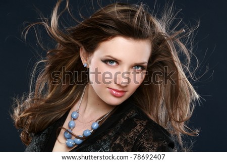 Beautiful long haired brunette. Studio portrait on dark-blue background