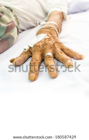 old patient\'s hand with plug on bed in hospital and blank area at lower side for fill text