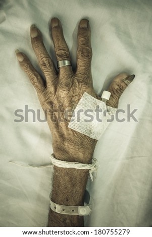 hand of old patient with plug on bed in hospital (vignette style)