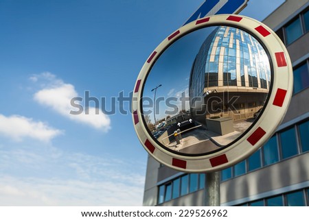 Convex mirror at a street reflecting a barrier entrance in underground garage