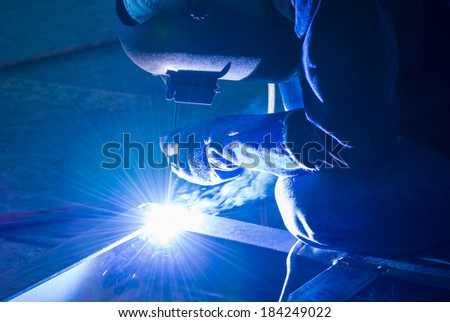 Welder working a welding metal work with protective mask and sparks for construction plant