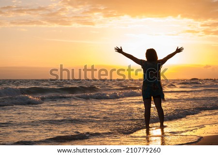 Young lady dances alone at the tropical beach, sunset