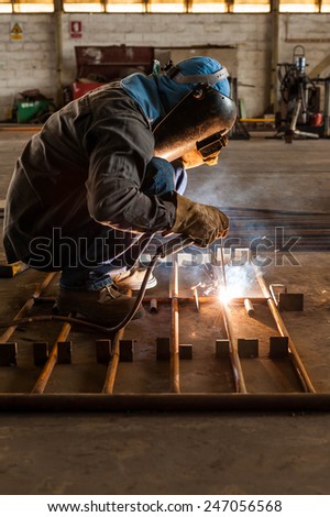 Worker with protective mask welding metal structure