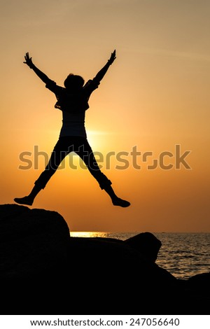 Successful woman jumping, dancing and having fun on sunset in beach. Freedom and happiness concept. Girl celebrating work out success.