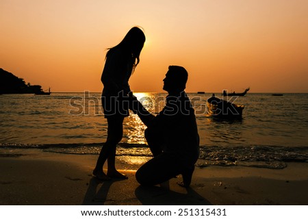 Couple in love back light silhouette at sea orange sunset