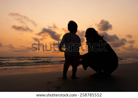 Silhouette of mother and little daughter on the beach