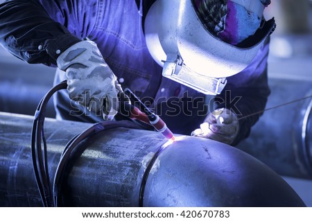 Worker welding metal piping using tig welder