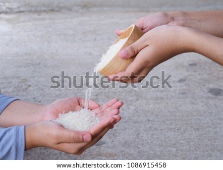 Women hands giving the rice in wooden bowl for some one.Arabic text is spell zakat and ramadan kareem ,This means the donation is important in Ramadan.