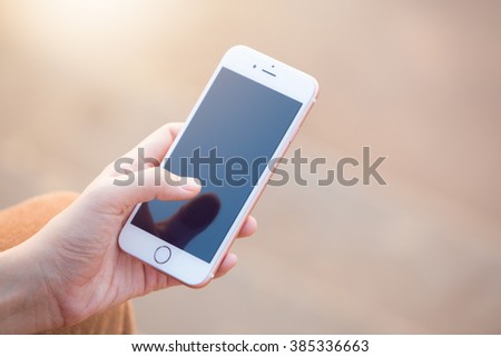 Beautiful young woman\'s hand using smart phone at beach,flare light