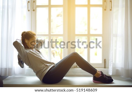 Attractive female doing exercise in her living room.She doing abs.Workout,flare light