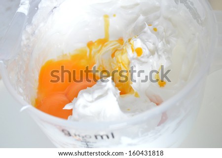 Beaten egg whites from yolks in a bowl with spoon