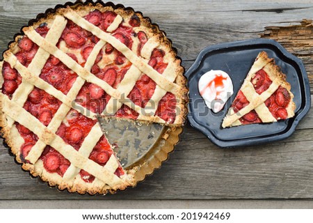 Strawberry tart on a black plate and background with wooden planks