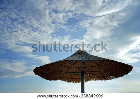 Straw sun umbrella in the evening sky blue