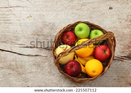 Variety of fruits into basket on old wood floor