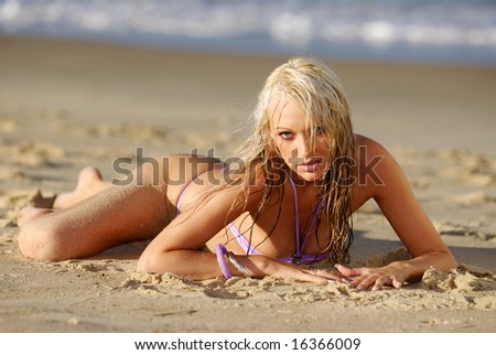 Beautiful blonde girl in bikini, laying on the beach.