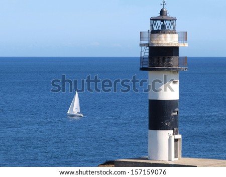 Lighthouse and boat. Lighthouse on the coast  and boat sailing