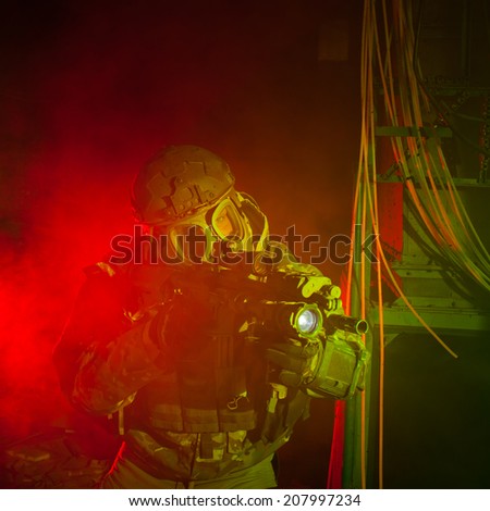 Special forces soldier with gas mask during the night mission (red and green light for underline the atmosphere)