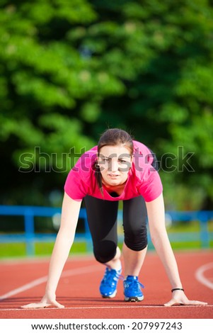 Beautiful young woman athlete in starting position ready to race (color toned image)