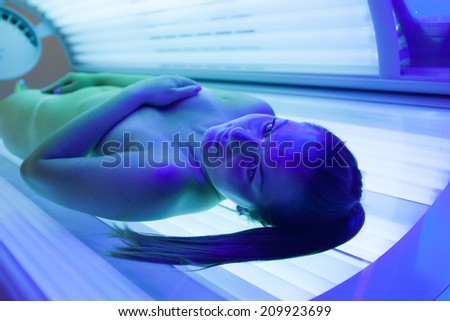 Pretty young woman tanning her skin in a modern solarium