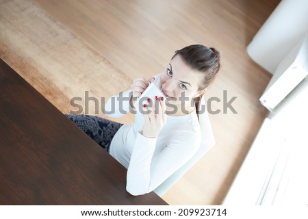 Beautiful young attractive woman drinking coffee/tea at the morning in the kitchen/living room in a modern flat