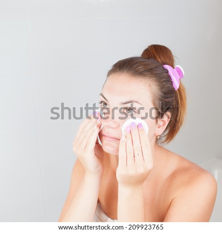 Portrait of young beautiful woman cleaning her face with cotton pads