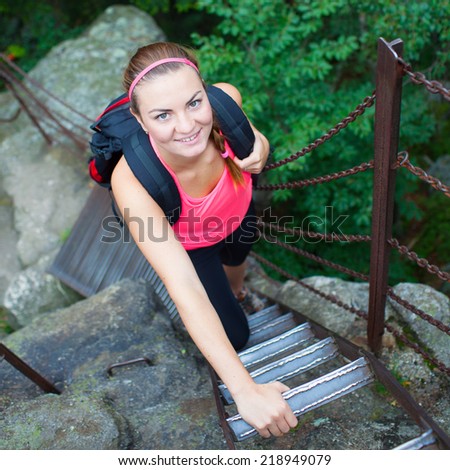 Young attractive woman/female tourist climbing the ladder on the top of hill/mountain/rock (shallow DOF, colorful image)