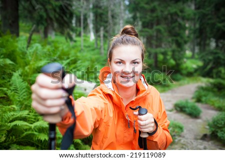 Active attractive young woman/female tourist nordic walking outdoors on a forest path, enjoying beauty of nature in national park (colorful image, shallow DOF)