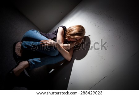 Young woman suffering from a severe depression, anxiety (very harsh lighting is used on this shot to underline the gloomy mood of the scene, color toned image)