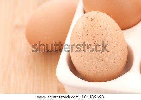 Three Brown Eggs, Natural and Organic, Fresh from the Chicken in a Contemporary or Modern Still Life in White Container and on Bamboo Cutting Board.  Horizontal with Copy Space.
