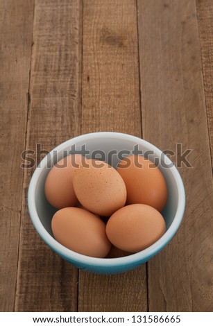 Brown Eggs Fresh from the Chicken Farm in a Vintage Bowl on a Rustic Kitchen Counter with copyspace above.
