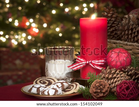 Christmas Cookies and Milk Waiting for Santa Claus in Candle Light with a Lighted Christmas Tree in the background on Christmas Eve