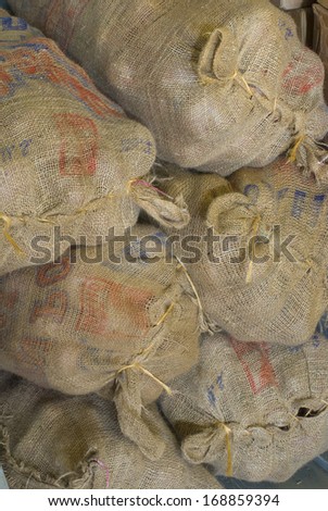 Big Burlap Bags of Red Potatoes stacked in a Farmers Market for Sale. Vertical.  Could be a brown, rustic, textured background