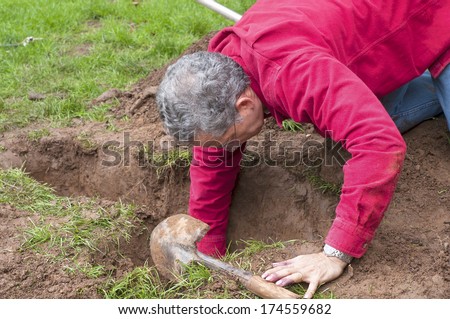 Man Preparing Hole in Ground for Installation of New PVC Pipes for in ground Sprinkler System in a Yard