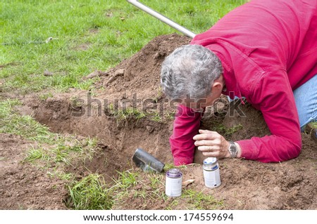 Man Working with Pipes in Ground while Installing a New Underground Sprinkler System to Water the Yard