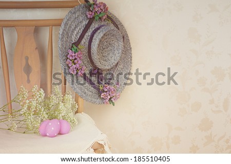 Vintage, Old Time Easter Still Life of Easter Eggs in a Chair with an Old Fashioned Womans Hat Hanging on it.  Against Floral Wallpaper with space for copy, text