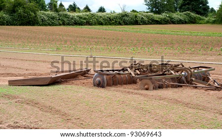 Farm Equipment Called a Disc with a Drift Board Behind it for Tilling Dirt and then Smoothing It in a Farm Landscape Scene in the Country