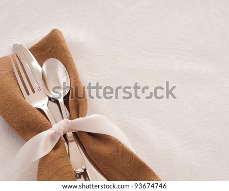 Antique Silverware Place Setting in a Brown Napkin and Tied with a Satin Ribbon against a White Background, a Table Cloth with Room for Text or Copy