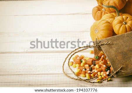 Candy Corn Spilling from Burlap Bag on Rustic White Wood Board Background with room or space for copy, text.   Horizontal, vintage sepia processing