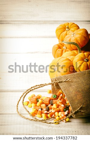 Candy Corn Spilling from Burlap Bag on Rustic White Wood Board Background with room or space for copy, text.   Vertical, vintage sepia processing