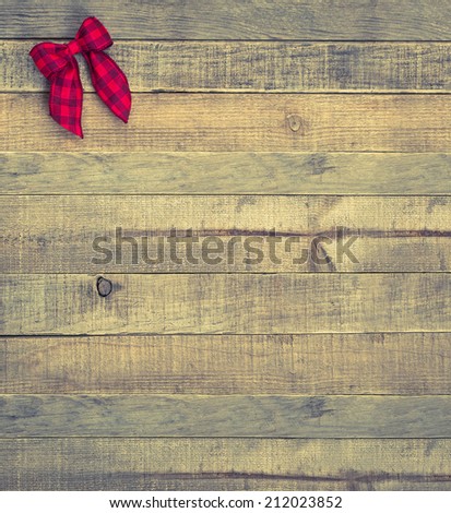 Red Checked Christmas Bow in upper corner on Rustic Wood Board Background with room or space for copy, text, words.  Vintage instagram vertical that can be cropped to horizontal