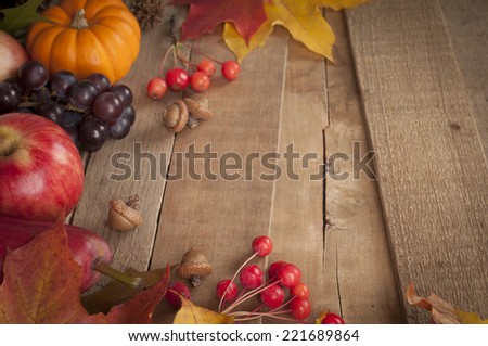 Pretty Fall Vignette with Mini Pumpkin, Apple, Red Pear, Nuts, Grapes, leaves and berries on rustic barn wood boards with room or space for copy, text, words.  Horizontal, above view at angle