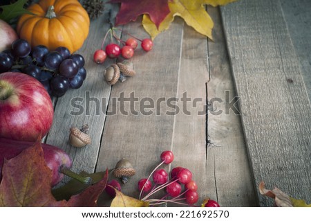 Pretty Fall Vignette with Mini Pumpkin, Grapes, Apple, Pear, Nuts, Leaves on Rustic Used Board Background with empty space for copy, text, words.  Horizontal above view, cool toned.