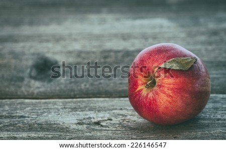 One Bright Red and Ready to eat Gala Apple in Rustic Barn Setting with Old Wood Boards and room or space for copy, text, your words.  Horizontal closeup, short dept of field, vintage grunge