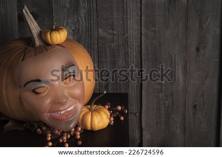 Creepy Vintage 60s Halloween Mask with Pumpkins against Rustic Wood Background.  Room or space for copy, text, your words.   horizontal