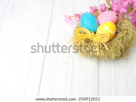 Pretty Easter Eggs in Nest with Pink Flowers in top corner of framework on Rustic White Wash Painted Used Boards with empty, blank room or space for copy, text, your words.  Horizontal Shabby Chic