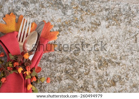 Closeup Above View of a Pretty Fall Place Setting with Silver fork, knife, and spoon on Rustic Stone Background with Room or Space for Copy, text, your words.  Horizontal Looking Down