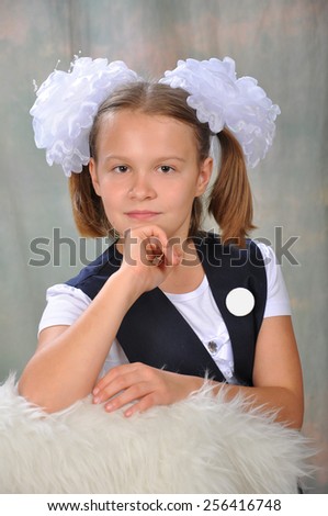 The schoolgirl in a school uniform with a white bow and a badge