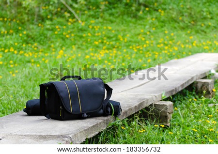 The Camera bag on the yellow daisy and grass field
