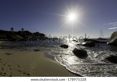 Caribbean sand beach with sun and rock formations