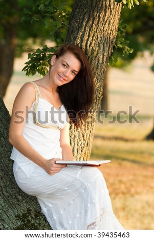 Portrait of a beautiful woman reading a book in woods